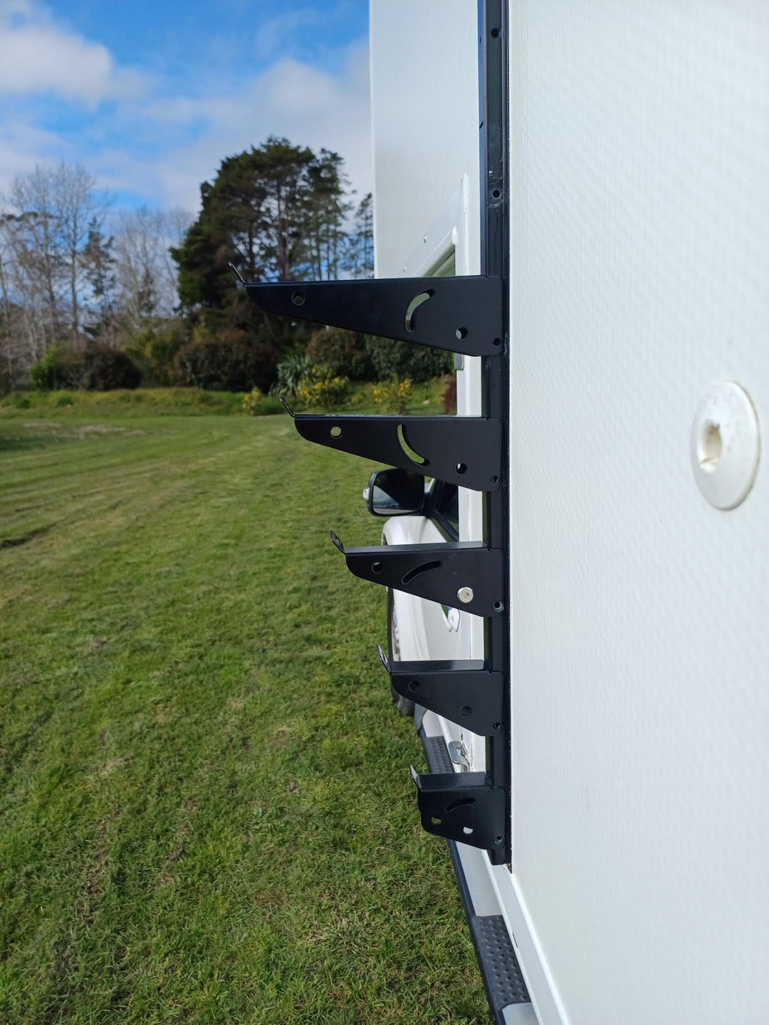 Side mount cargo racks for motorhomes and caravans